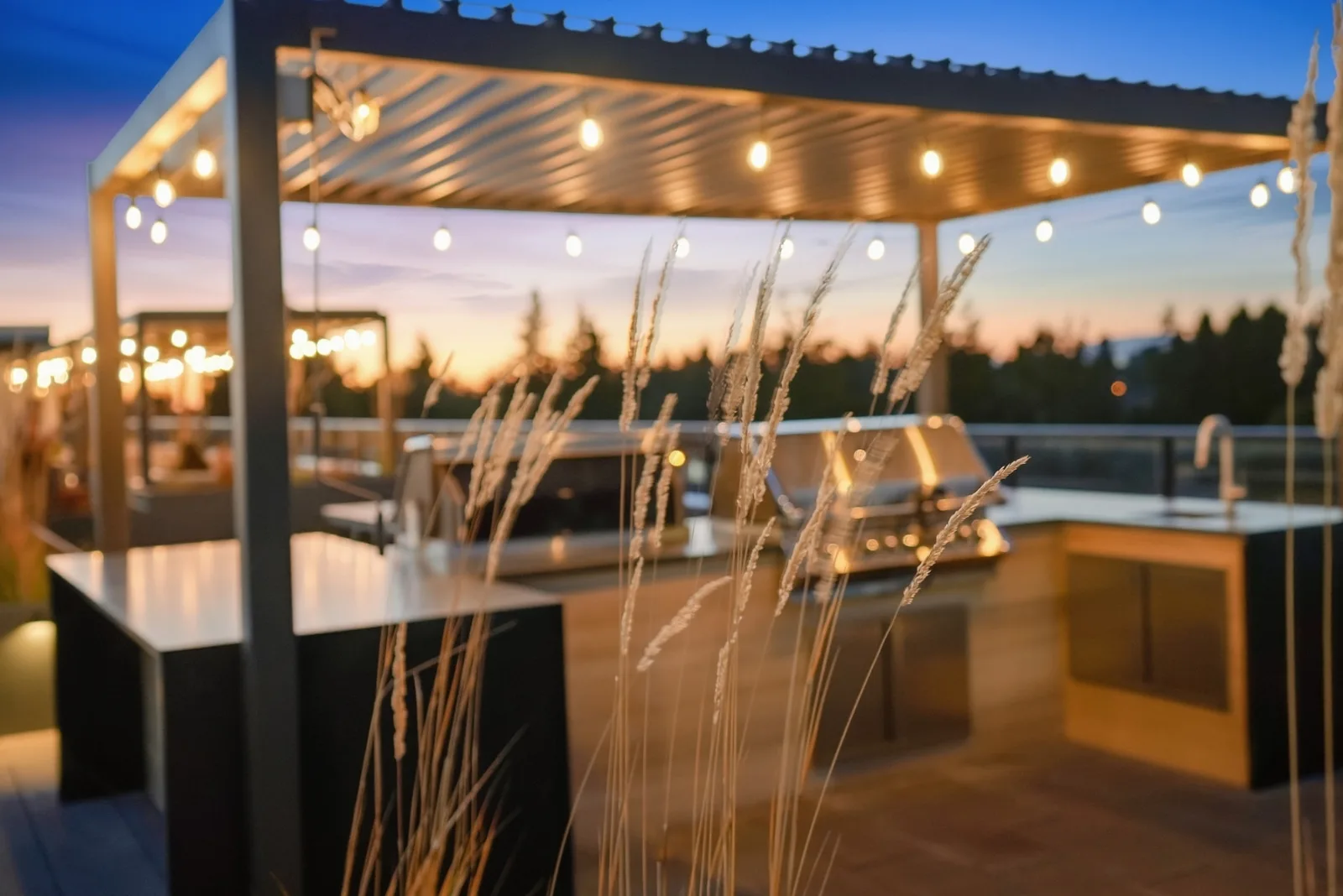 Rooftop outdoor kitchen with built-in grills under a pergola at dusk at Scott + 77, North Delta